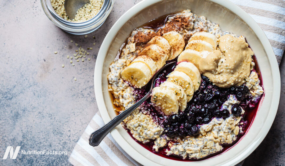 bowl of oatmeal topped with seeds, banana, blueberries, and nut butter